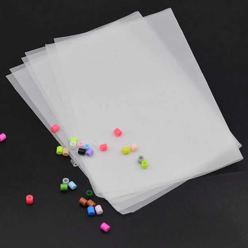 A set of precision hama beads tweezers with various colored plastic beads displayed on a sheet of clear plastic.