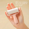A hand holds a small, pink lint roller with a white roller, demonstrating its compact size.