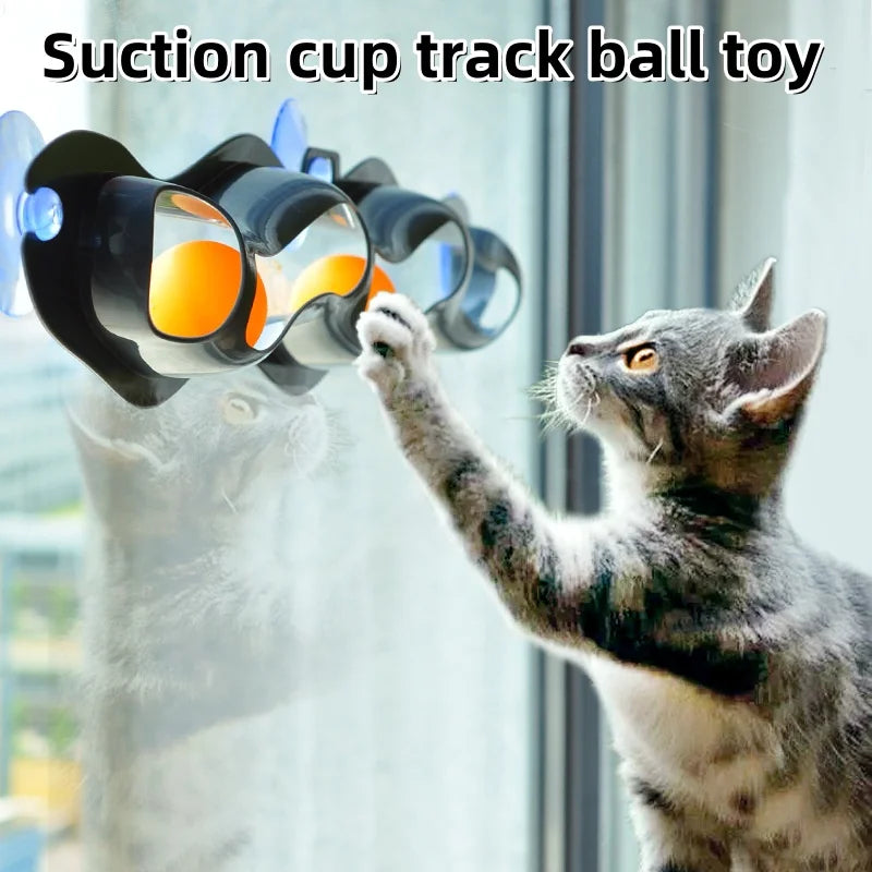 Un chat gris joue avec un jouet balle à trackball avec des balles orange et jaunes.