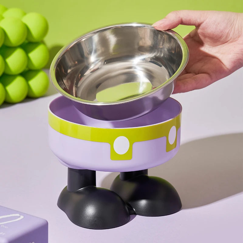 A hand holds an elevated stainless steel pet bowl with a purple base and black stand.