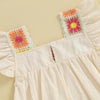 A light pink toddler romper featuring floral embroidery details on the chest and ruffled sleeves.