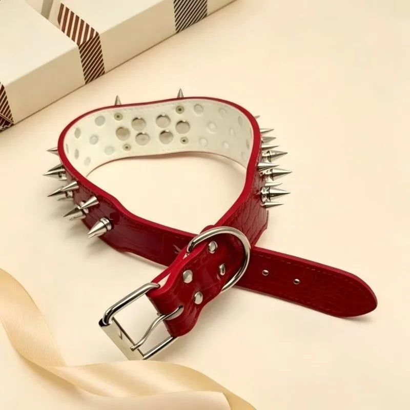 A red spiked leather dog collar with a silver buckle lying on a light surface.