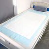 A white bed with a light blue fitted sheet and a blue pillow, showing high-absorbency disposable pads.