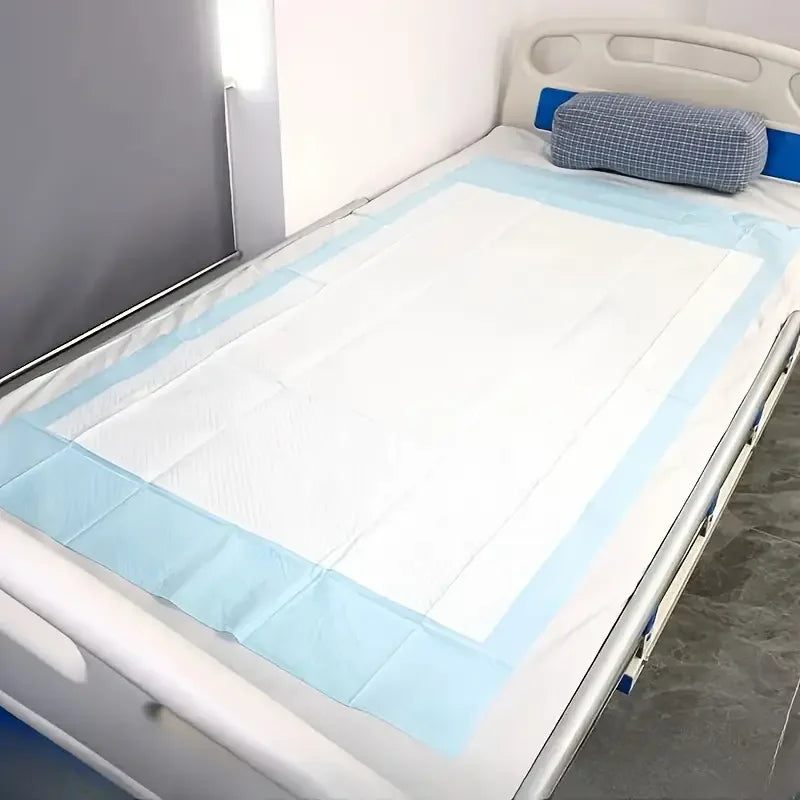 A white bed with a light blue fitted sheet and a blue pillow, showing high-absorbency disposable pads.