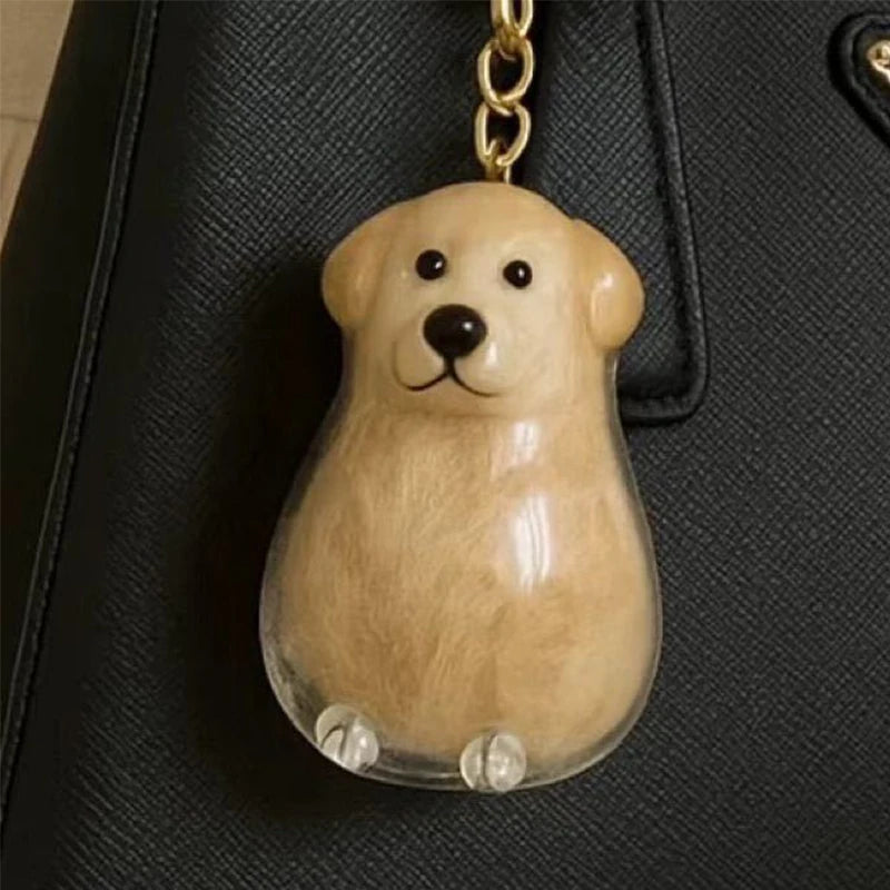 Klares Harz-Hund-Anhänger mit braunem Körper und schwarzer Nase, an einem goldfarbenen Schlüsselanhänger.