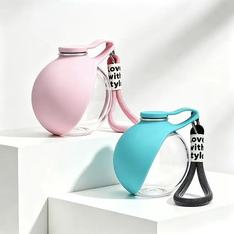 A pink glass portable dog water bottle with a silicone strap and a blue glass bottle with a black strap.