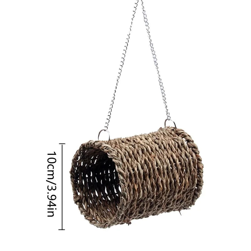 A natural grass hanging bird nest with a cylindrical shape and a dark interior.