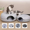 A gray cat is sitting on a round, soft pet bed with an entrance, next to four views of the donut tunnel cat bed.