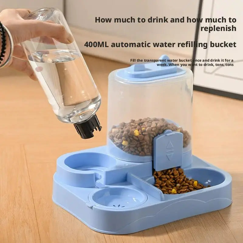 A blue gravity-fed pet food dispenser with a water bowl for cats and small dogs is shown next to a hand pouring water into th