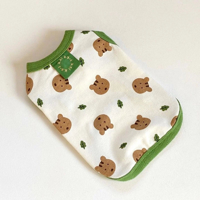 A white pet vest with brown cartoon dog prints and a green trim.