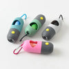 A collection of capsule dog waste bag dispensers in various colors, including teal, green, and pink, with attached loops.