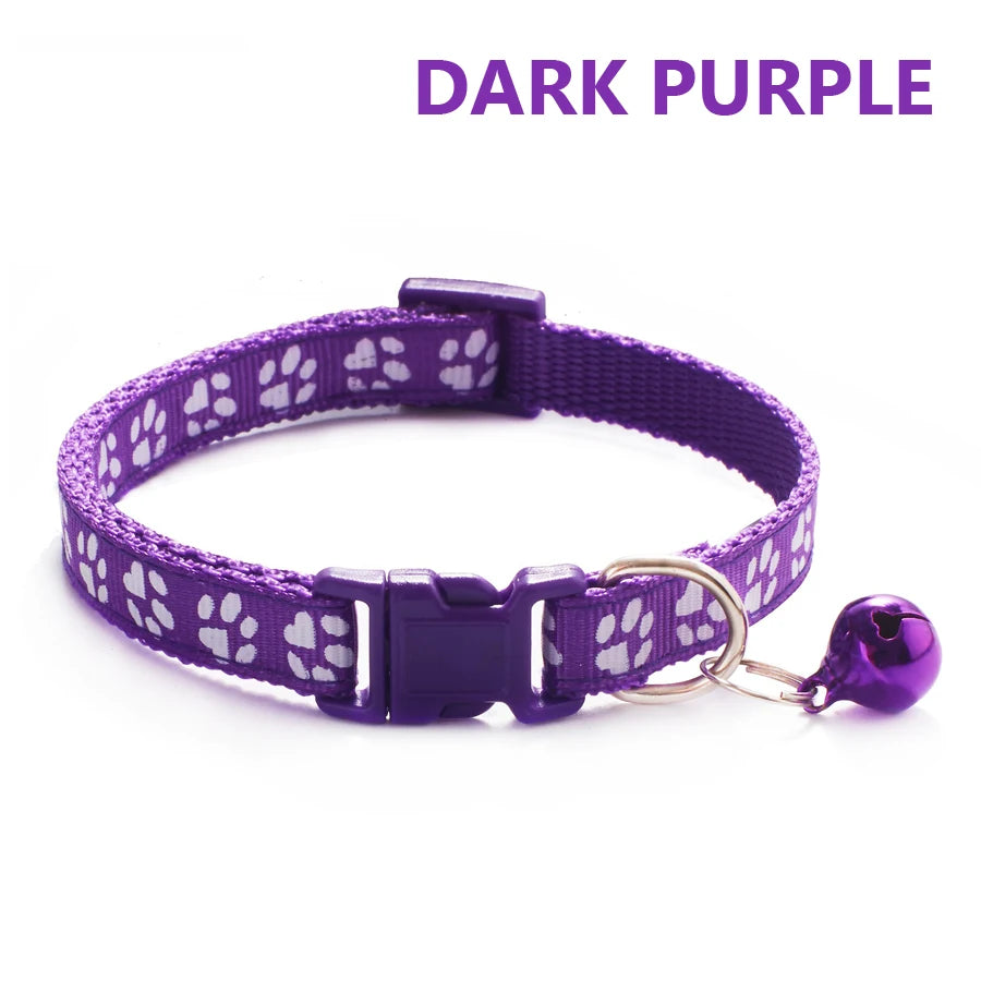 A dark purple adjustable pet collar with a paw print pattern and a bell attached.