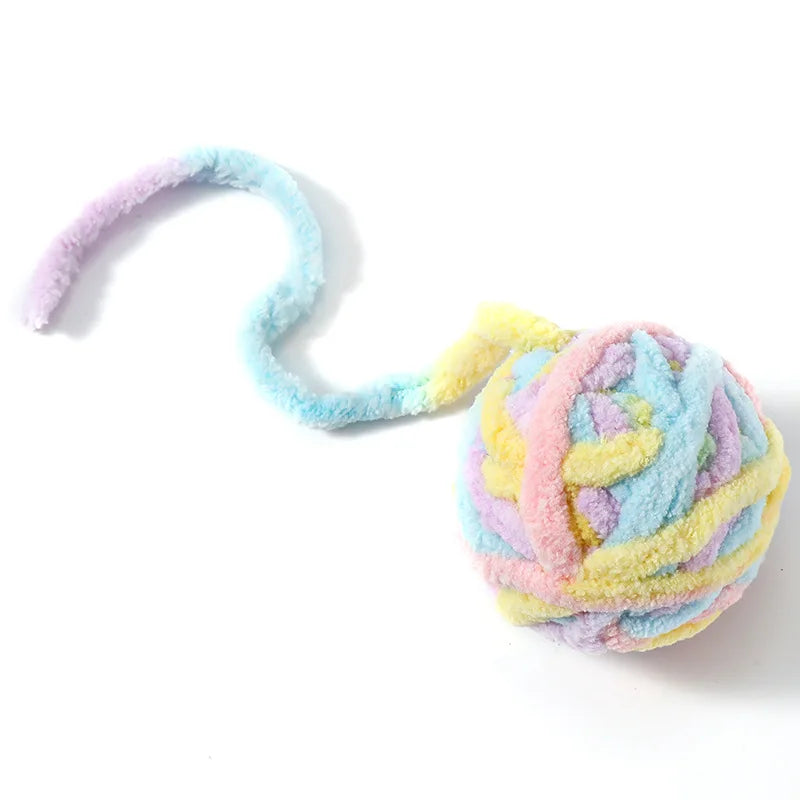 A soft plush cat toy ball with a bell, featuring multicolored pastel fibers in pink, blue, and yellow.