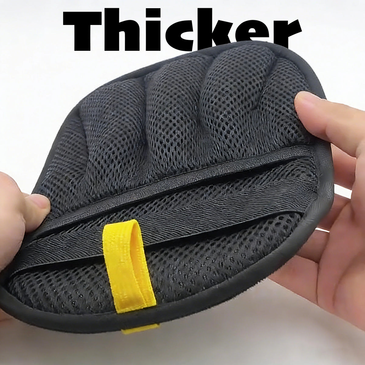 A hand holds a black reusable pet grooming glove with a yellow accent on the palm side.