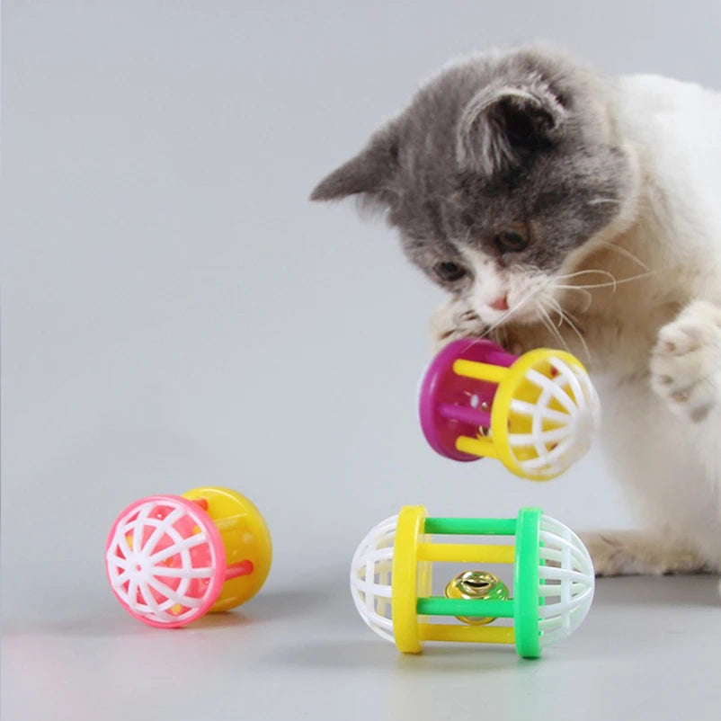 A tabby cat is interacting with a yellow and pink cat toy ball.