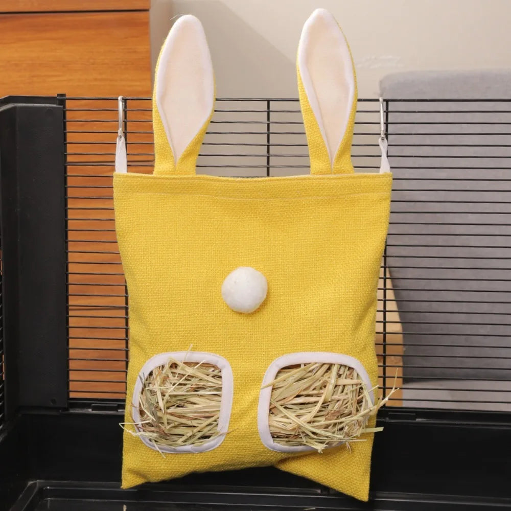 A yellow multi-hole hay feeder bag with white ears and a round white nose is displayed in a dark container.