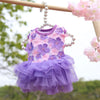 Robe en dentelle de chiffon florale violette et rose pour chien, suspendue à une balustrade en bois dehors.