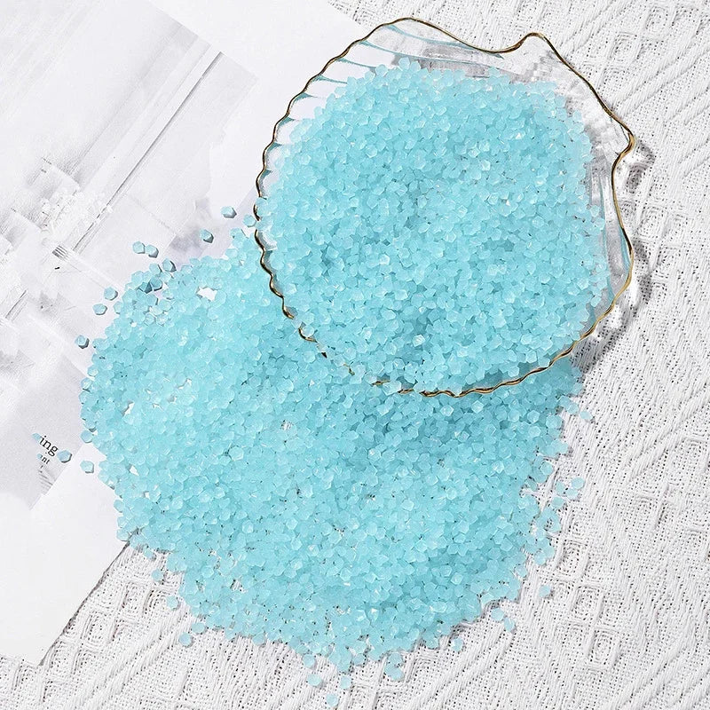 A pile of glowing light blue decorative pebbles scattered on a white textured surface.