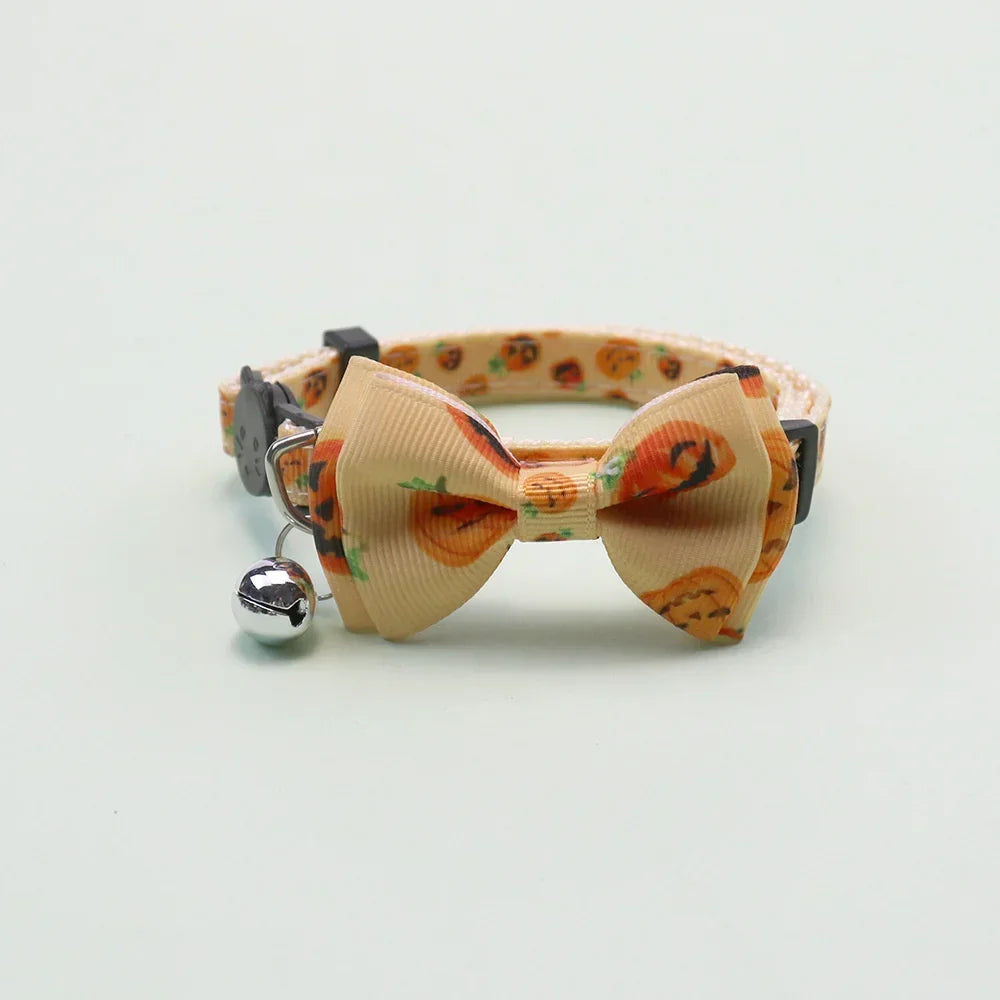 An adjustable pet collar featuring an orange pumpkin print fabric and a bow tie with a silver bell.