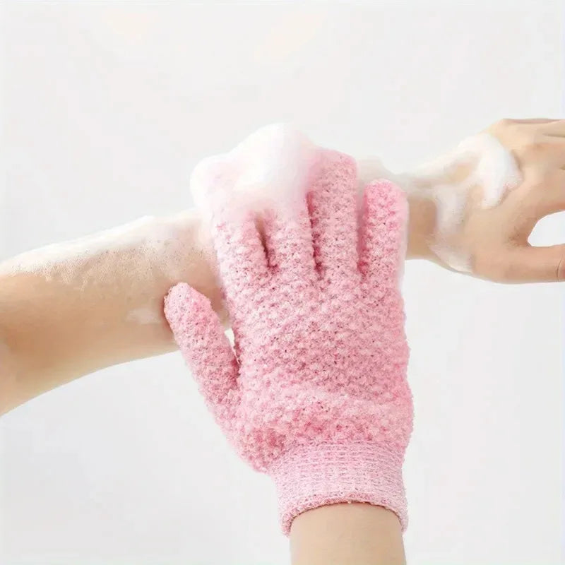 A hand wearing a pink exfoliating shower glove with white foam on the skin.