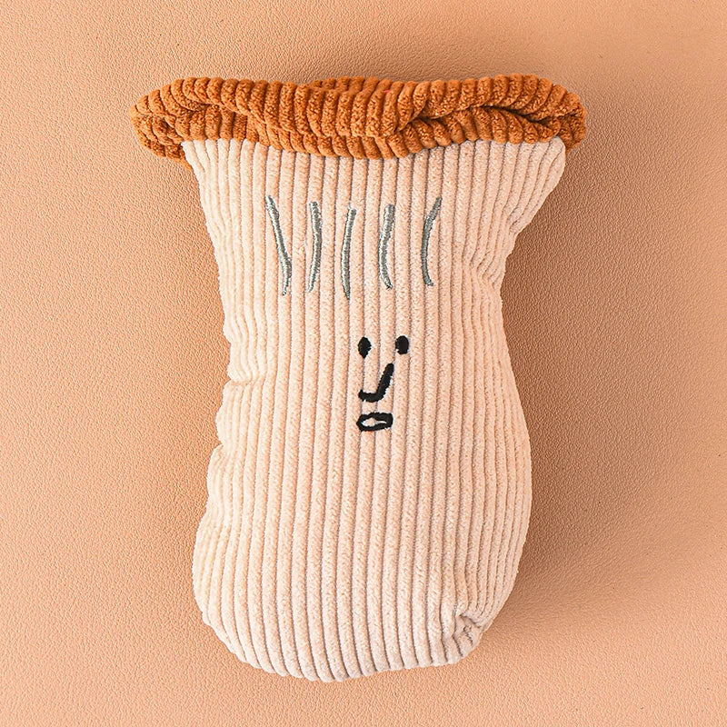 Jouet en peluche beige clair en forme de jambe, avec un haut tricoté orange et des détails faciaux gris.