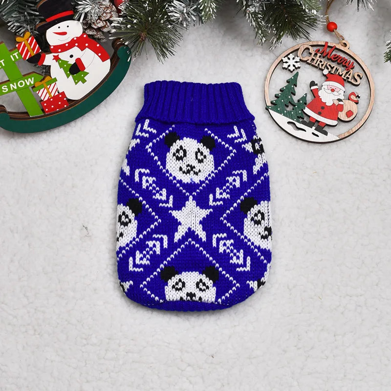 A navy blue knitted sweater featuring a white pattern of panda faces and snowflakes, displayed with Christmas decorations.