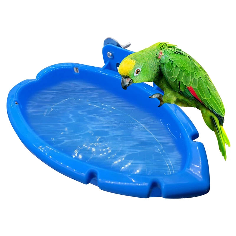 A vibrant green parrot is perched on a bright blue durable food and bath tray.