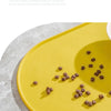 A yellow feeding mat with a full circle edge design, showing scattered dry pet food on the surface.