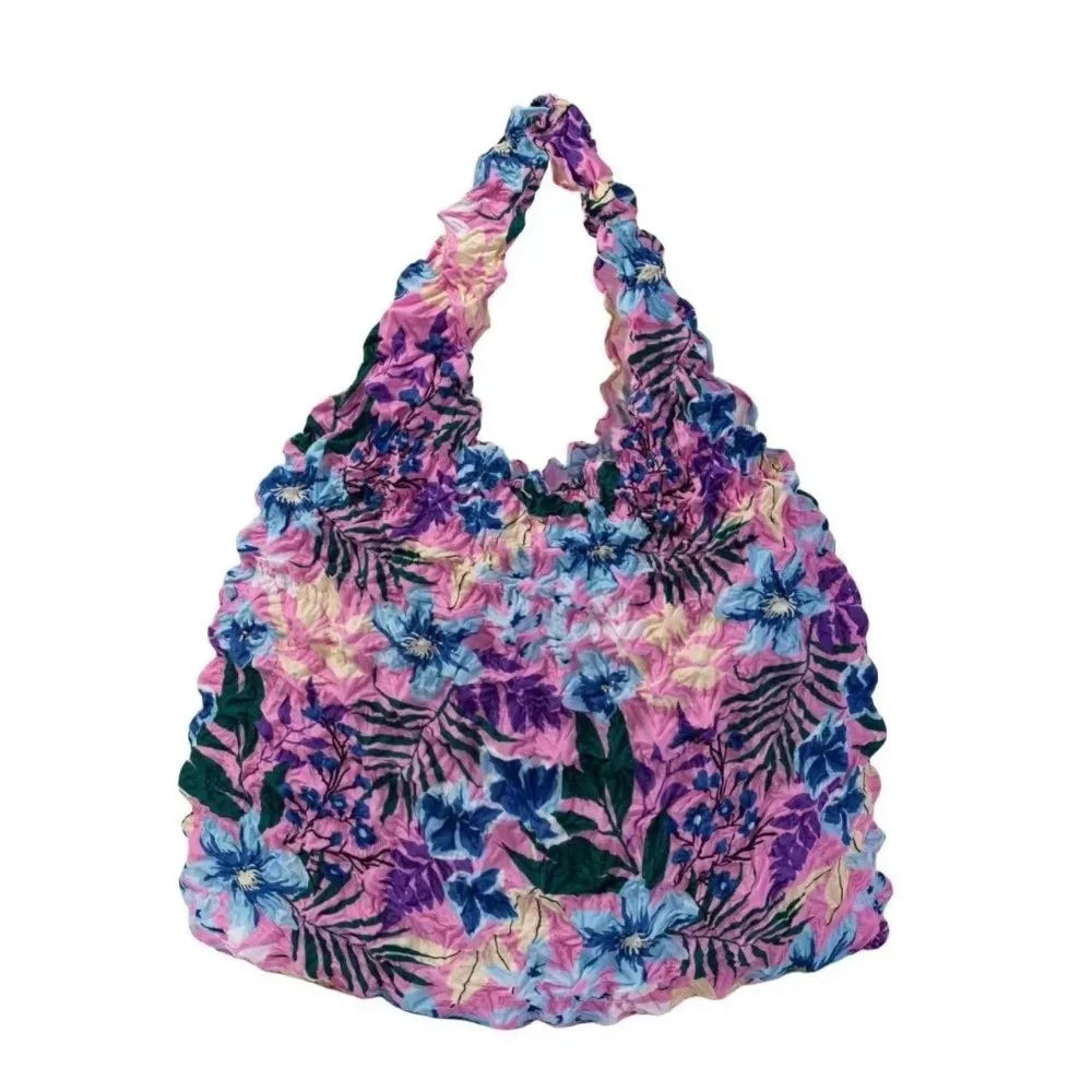 A floral patterned fabric tote bag featuring shades of purple, pink, and blue flowers and leaves.