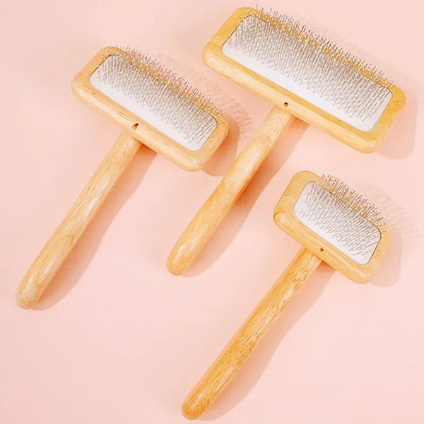 Three wooden pet grooming brushes with massage bristles displayed on a pink background.
