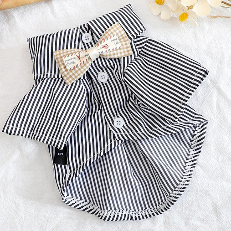 A black and white striped pet shirt with a bow tie is displayed on a white surface.