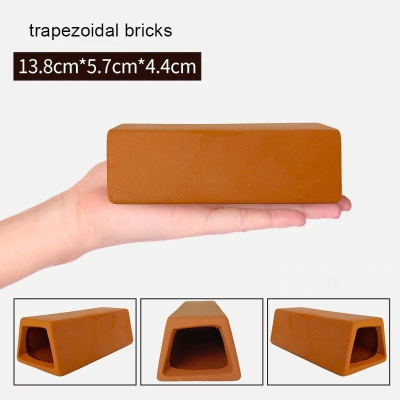 A hand holds a terracotta trapezoidal brick, showing its shape and texture.
