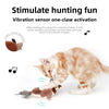 A fluffy orange tabby cat is interacting with an electronic toy that simulates a bird with flapping wings and vibration senso