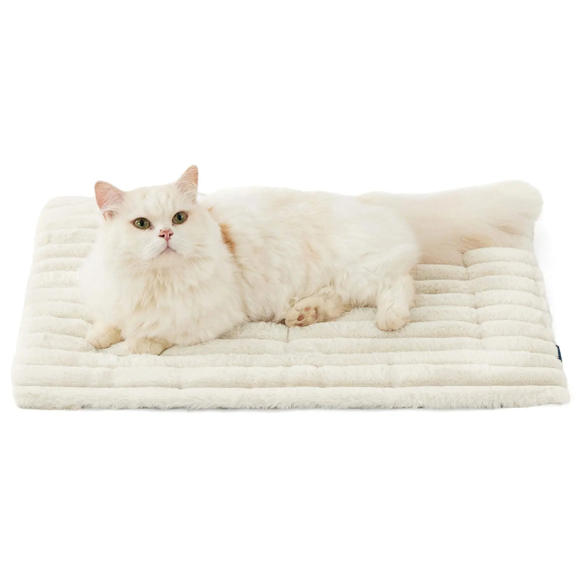 A fluffy white cat lying on a beige self-warming pet mat.