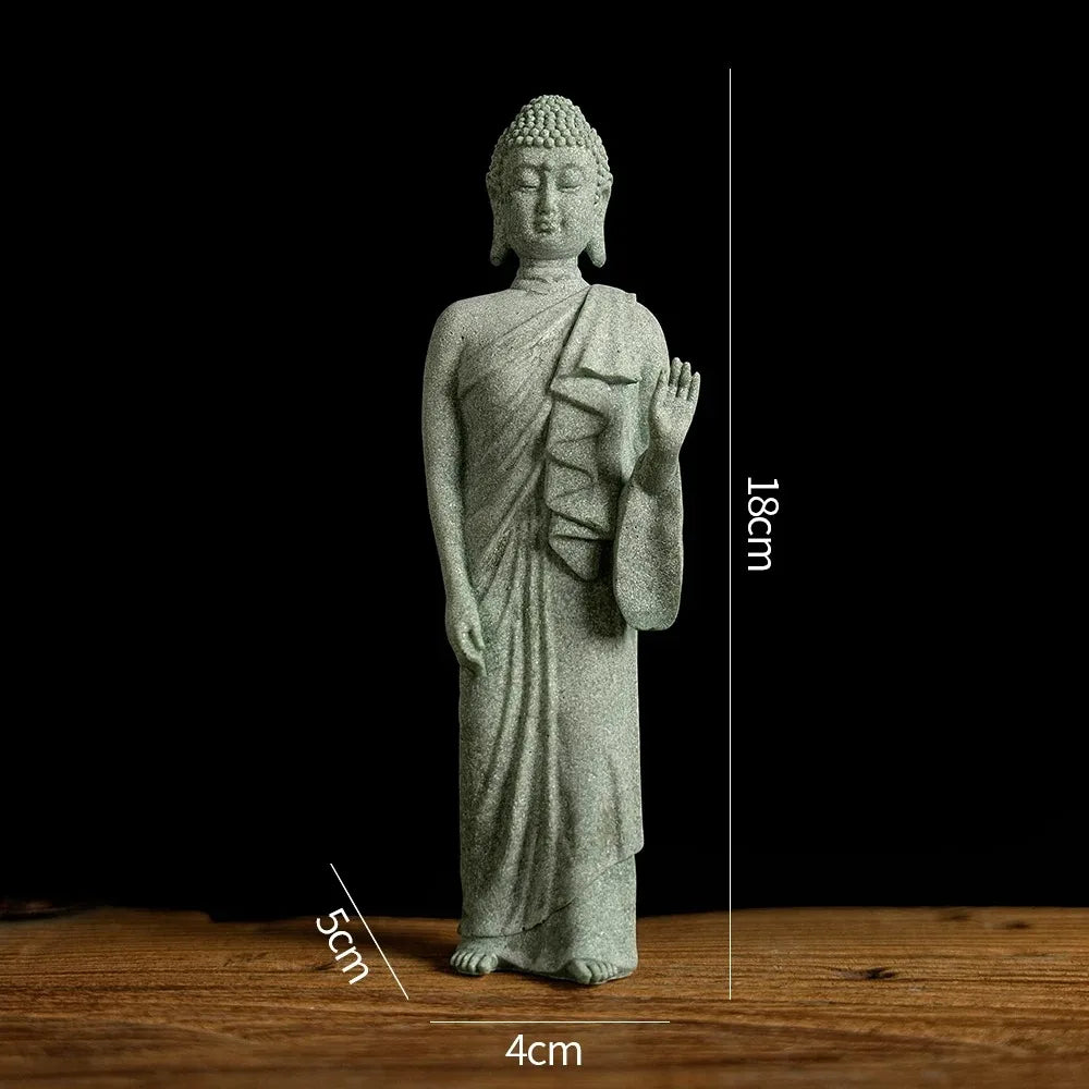 A light gray Buddha stone statue with hands raised, standing on a wooden surface.