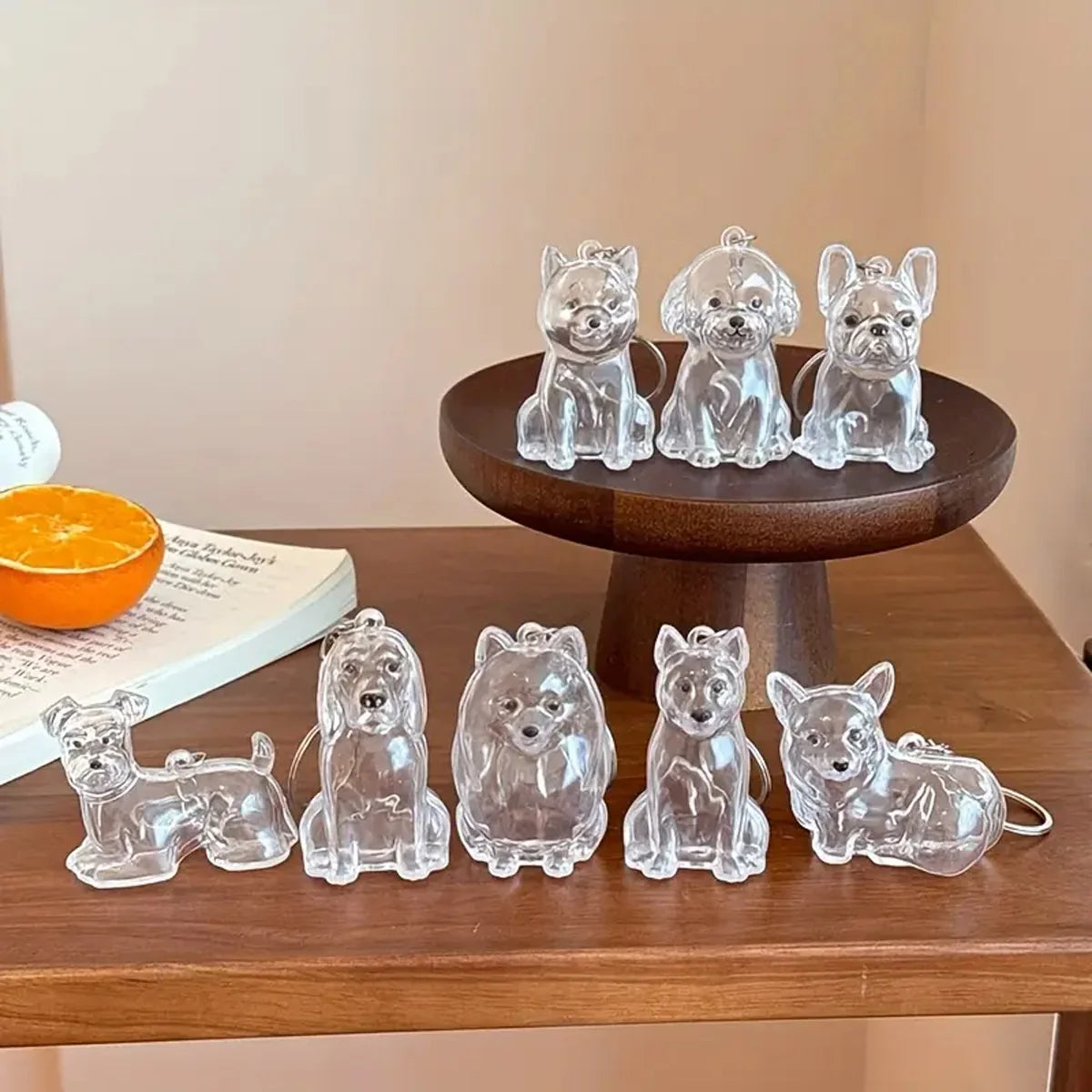 A collection of clear acrylic pet hair storage keychains featuring various dog breeds arranged on a dark wooden stand.