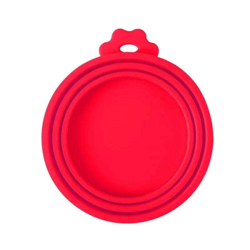 A bright red reusable silicone pet food can lid with a spoon.