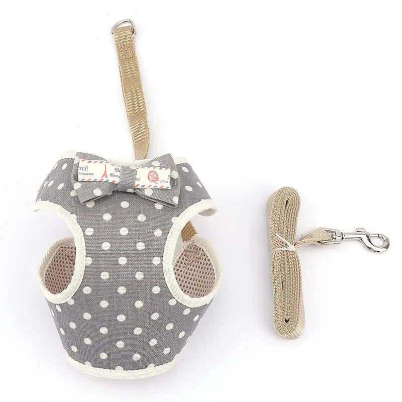 A gray polka dot mesh vest cat harness and leash set with a bow and adjustable strap.
