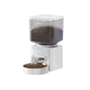A white smart automatic pet feeder with a clear top, dispensing dark pet food into a removable bowl.