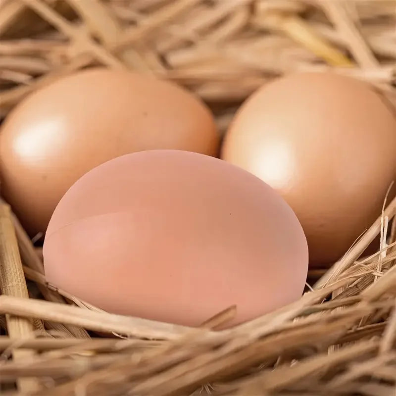 A single pink plastic chicken egg rests in a natural straw nest.