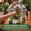 Eine Hand legt einen Finger auf die Glas-Tür eines klaren Kunststoffterrariums für kleine Haustiere.
