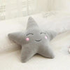 A gray star-shaped plush pillow resting on white bedding.