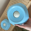 Una mano sostiene un cuenco para perros interactivo de alimentación lenta azul claro con superficies texturizadas.