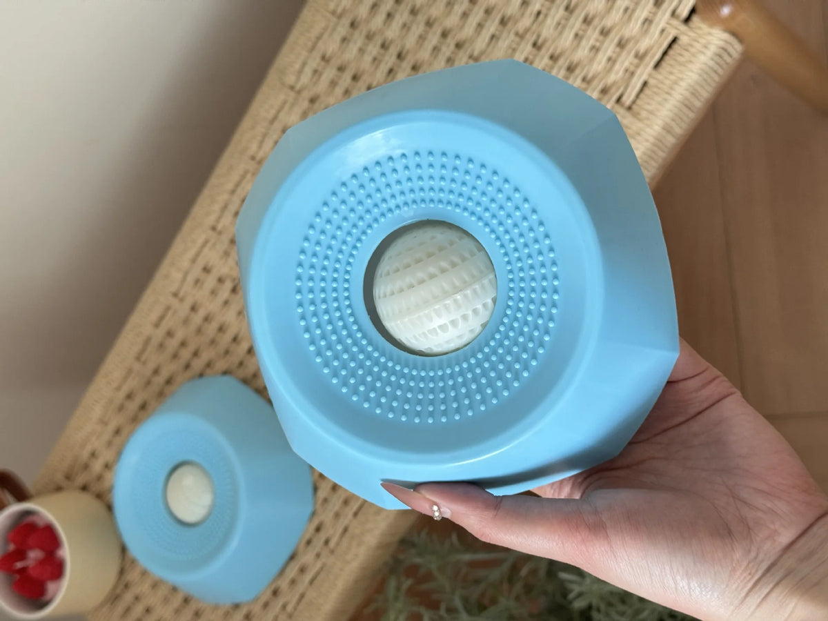 Una mano sostiene un cuenco para perros interactivo de alimentación lenta azul claro con superficies texturizadas.