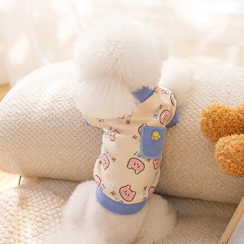 A light beige pet vest for a dog with a fluffy white trim and cartoon print details.