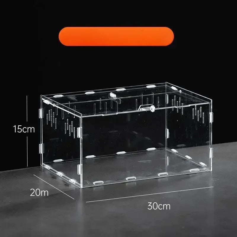 A rectangular transparent acrylic reptile terrarium resting on a dark surface.