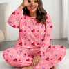 A woman models a pink heart print pajama set while making a peace sign.
