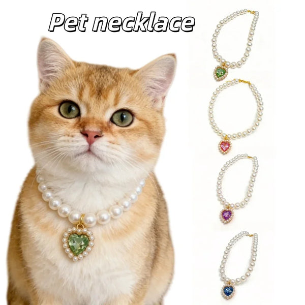 An orange tabby kitten wearing a pearl necklace with a green pendant and several other pearl necklaces.