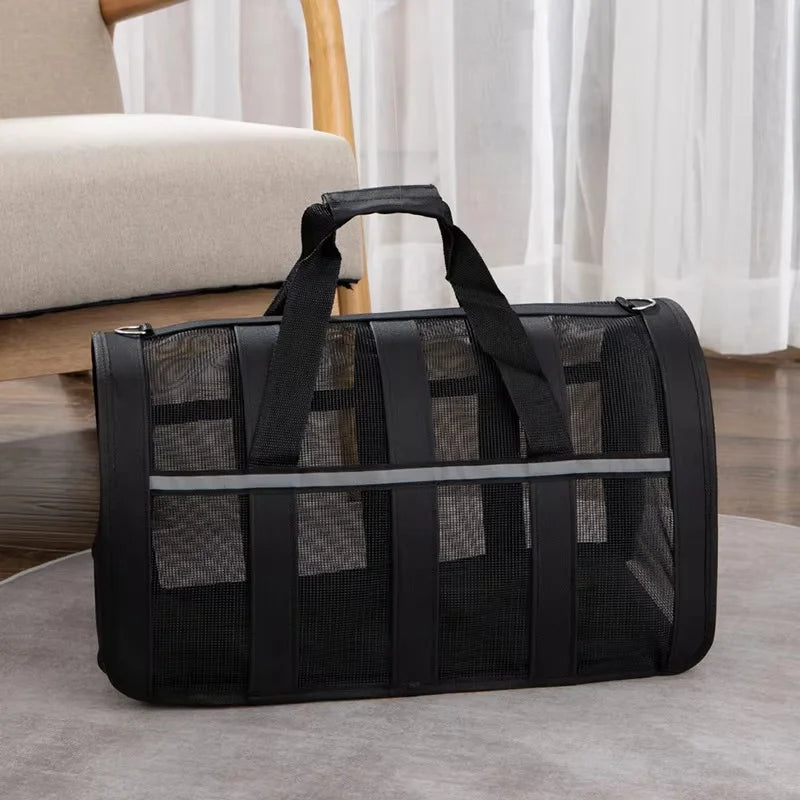 Black lightweight foldable mesh travel carrier bag with handles resting on a gray surface.