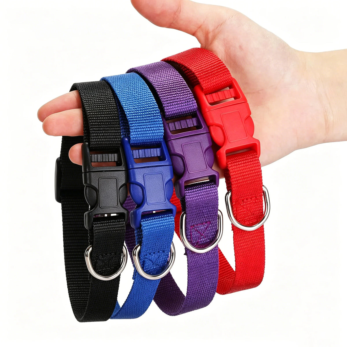 A hand holds a stack of colorful nylon dog collars in various shades including black, blue, purple, and red.